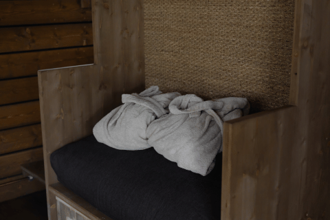Due accappatoi piegati su una panca di legno nella cabina Comfort Sweet Wellness di Cosy Cabins, Limburg, Belgio.