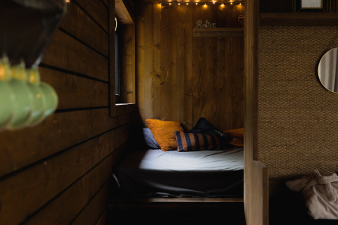 Accogliente cabina con pareti in legno, letto e cuscini a Comfort Sweet Wellness, Limburgo, Belgio.