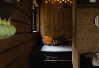 Accogliente cabina con pareti in legno, letto e cuscini a Comfort Sweet Wellness, Limburgo, Belgio.