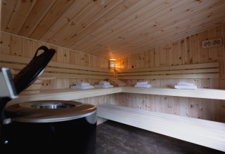 Interno di una sauna accogliente in legno con panche e asciugamani in una cabina wellness nella foresta.