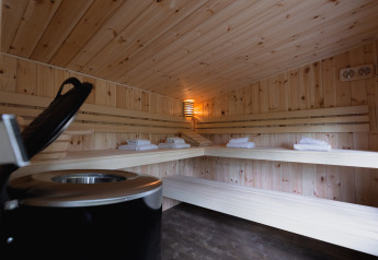 Interno di una sauna accogliente in legno con panche e asciugamani in una cabina wellness nella foresta.