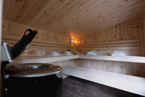 Intérieur d'un sauna en bois chaleureux avec bancs et serviettes dans une cabine bien-être en forêt.