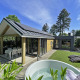 Buitenbeeld van Wellness Cottage bij De Thijmse Berg in Nederland met jacuzzi, ligstoelen en tuin.