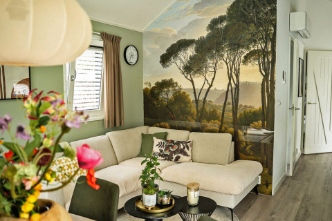 Sala moderna en Wellness Cottage de De Thijmse Berg con mural de bosque y cómodo sofá claro en la esquina.