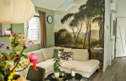 Soggiorno moderno al Wellness Cottage di De Thijmse Berg con murale di foresta e divano chiaro confortevole.