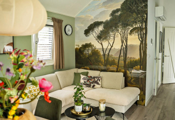 Moderne stue i Wellness Cottage ved De Thijmse Berg med vægmaleri af skovlandskab og komfortabel sofa.