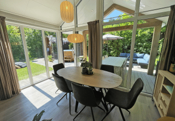 Comedor luminoso en Wellness Cottage de De Thijmse Berg, Países Bajos, con vistas a terraza y jardín.