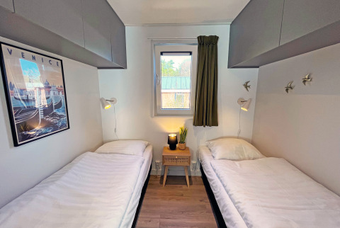 Dormitorio con dos camas individuales y decoración moderna en Wellness Cottage, De Thijmse Berg, Países Bajos.