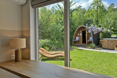 Uitzicht vanuit Wellness Cottage bij De Thijmse Berg in Nederland, met tuin, sauna en houten ligstoel.