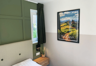 Dormitorio moderno en Wellness Cottage de De Thijmse Berg con póster de Toscana y detalles en verde.