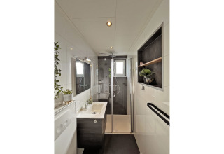 Bagno moderno al Wellness Cottage presso De Thijmse Berg, Paesi Bassi, con doccia in vetro e piante verdi.