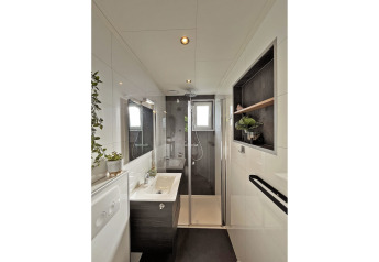 Moderne badeværelse i Wellness Cottage ved De Thijmse Berg i Holland med glasbruser og grønne planter.