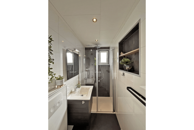 Salle de bain moderne au Wellness Cottage de De Thijmse Berg, Pays-Bas, avec douche en verre et plantes vertes.