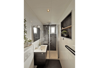 Modernes Badezimmer im Wellness Cottage bei De Thijmse Berg, Niederlande, mit Glasdusche und Pflanzen.