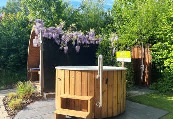 Udendørs wellnessområde i Wellness Cottage på De Thijmse Berg, med vildmarksbad, bruser og grønne omgivelser.