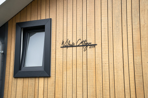 Fachada de Wellness Cottage en De Thijmse Berg, Países Bajos, con revestimiento de madera y ventana negra.