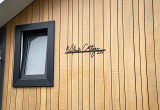 Fachada de Wellness Cottage en De Thijmse Berg, Países Bajos, con revestimiento de madera y ventana negra.