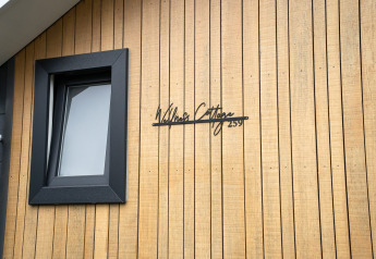 Facade af Wellness Cottage på De Thijmse Berg, Holland, med træbeklædning og sort vindue.