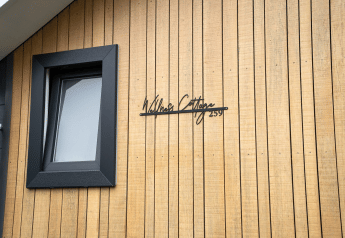 Façade du Wellness Cottage à De Thijmse Berg, Pays-Bas, avec bardage en bois et fenêtre noire.