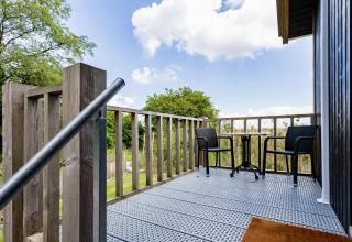 Small balcony with a table and two chairs at Tiny House XL at The Kremmer in the Netherlands, nature view.