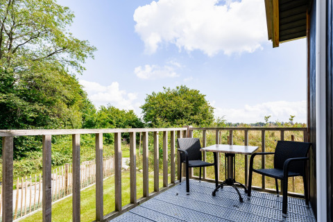 Balkon mit zwei Stühlen und Tisch im Tiny House XL bei The Kremmer in den Niederlanden, Naturblick.
