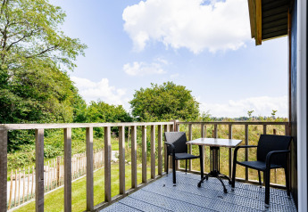 Balkon met twee stoelen en tafel bij Tiny House XL op The Kremmer in Nederland, uitzicht op natuur.