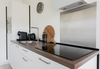 Pequeña cocina moderna con encimera negra, electrodomésticos y gabinetes blancos en Tiny House XL.