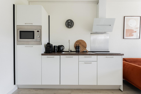 Moderne, kompaktes weißes Kücheninterieur im Tiny House XL bei The Kremmer, Niederlande, mit Geräten.