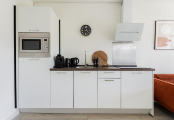 Moderne compacte witte keuken in Tiny House XL bij The Kremmer in Nederland met apparatuur en decoratie.