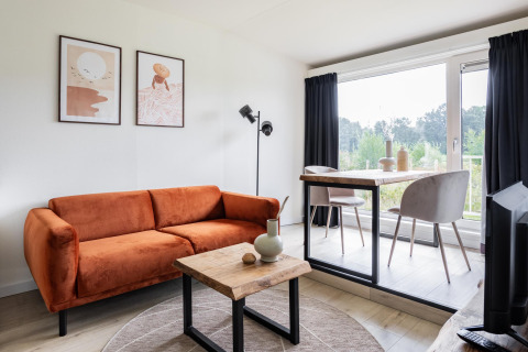 Modernes Wohnzimmer im Tiny House XL bei The Kremmer, Niederlande, mit rustikalem Charme und Panoramafenster.