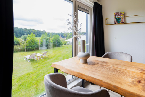 Blick vom Esstisch im Tiny House XL bei The Kremmer, Niederlande, auf Garten und Liegestühle außen.