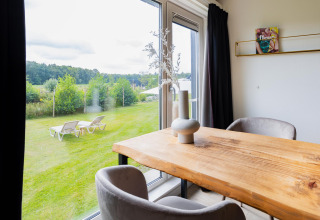 Blick vom Esstisch im Tiny House XL bei The Kremmer, Niederlande, auf Garten und Liegestühle außen.