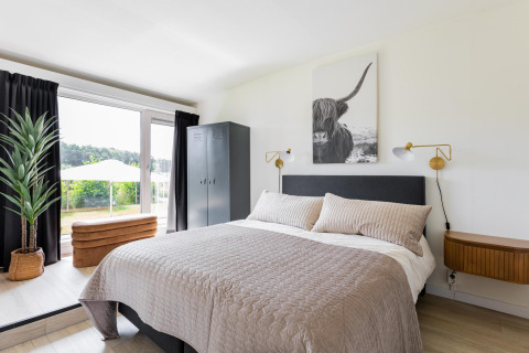 Slaapkamer in Tiny House XL bij The Kremmer in Nederland, met moderne inrichting en uitzicht op tuin.