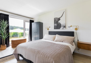 Slaapkamer in Tiny House XL bij The Kremmer in Nederland, met moderne inrichting en uitzicht op tuin.