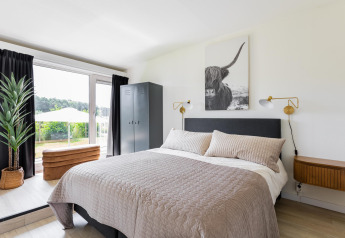 Schlafzimmer im Tiny House XL bei The Kremmer in den Niederlanden mit modernem Stil und Gartenblick.