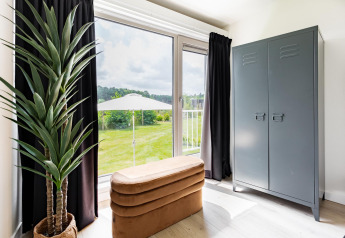 Lichte kamer in Tiny House XL bij The Kremmer, Nederland, met groot raam, moderne inrichting en groen uitzicht.