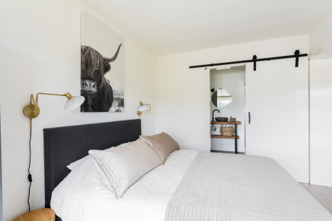 Schlafzimmer im Tiny House XL bei The Kremmer, Niederlande, mit modernem Design und Schiebetür zum Bad.