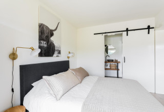 Schlafzimmer im Tiny House XL bei The Kremmer, Niederlande, mit modernem Design und Schiebetür zum Bad.