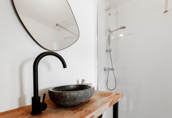 Baño moderno en Tiny House XL en The Kremmer, Países Bajos, con lavabo de piedra y ducha elegante.