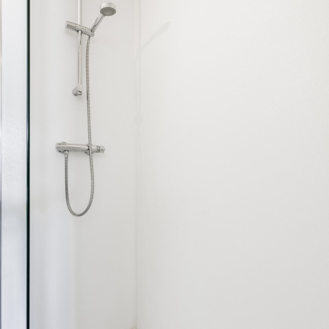 Moderne Dusche im Tiny House XL bei The Kremmer, Niederlande. Sauber, weiß und funktional gestaltet.