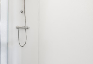Moderne Dusche im Tiny House XL bei The Kremmer, Niederlande. Sauber, weiß und funktional gestaltet.