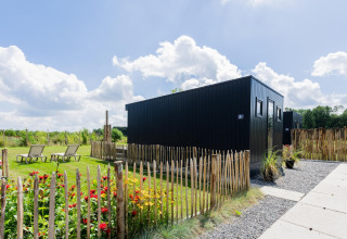Moderne tiny house met terras en tuin bij The Kremmer in Nederland, omgeven door een houten hek.