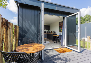 Tiny house met terras, open deuren, modern interieur en buitenzitje bij The Kremmer, Nederland.