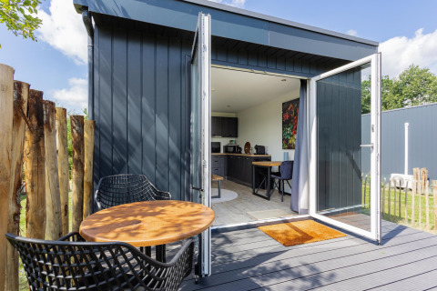 Tiny house with decking, open doors, modern interior, and outdoor seating at The Kremmer, Netherlands.