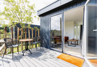 Zonnig terras met twee stoelen en een tafel bij Tiny House met vlonder bij The Kremmer, Nederland.