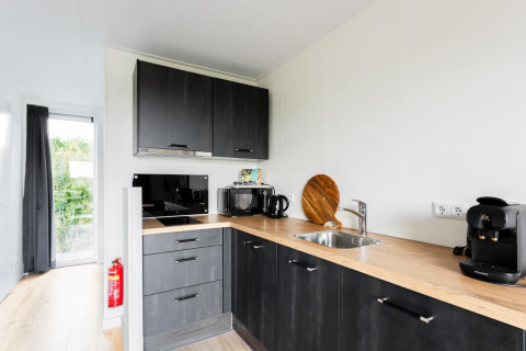 Cocina moderna en una Tiny House en The Kremmer, Países Bajos, con gabinetes oscuros y cafetera.