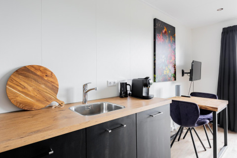 Moderne kitchenette in Tiny House met houten blad, spoelbak en koffiemachine bij The Kremmer, Nederland.