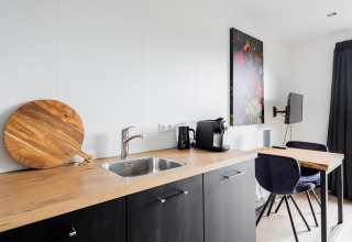 Cocina moderna de Tiny House con encimera de madera, fregadero y cafetera en The Kremmer, Países Bajos.