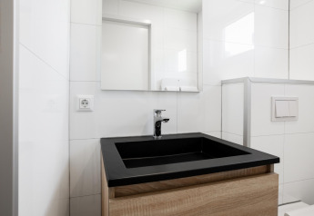 Baño moderno con lavabo negro y gabinete de madera en una tiny house en The Kremmer, Países Bajos.