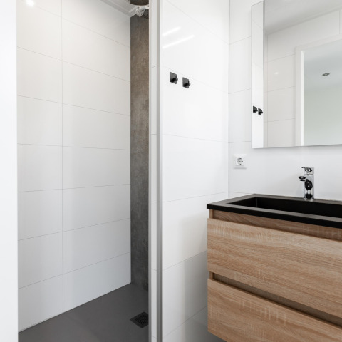 Modernes Badezimmer im Tiny House bei The Kremmer, Niederlande, mit Holzwaschbecken und Dusche.